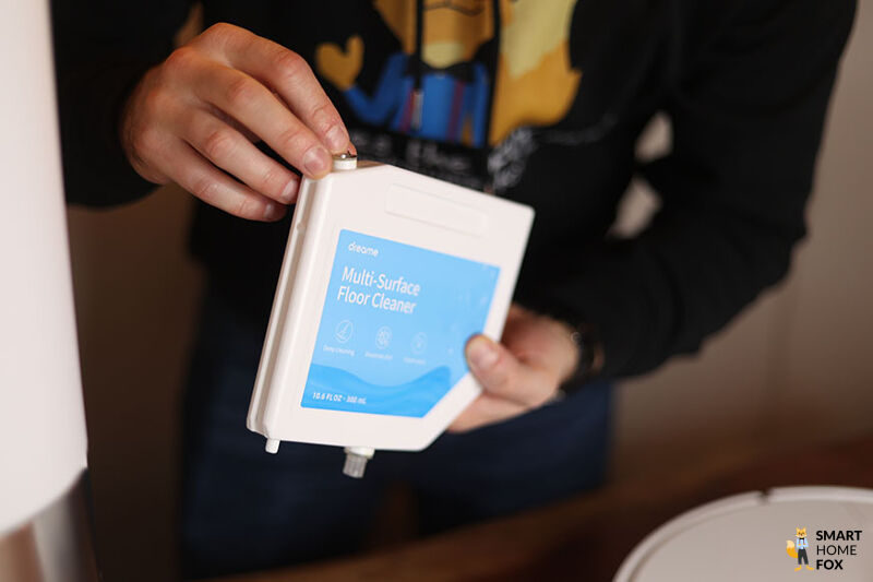 Die Kartusche mit dem Reinigungsmittel des Dreame L10s Ultra wird in den Händen gehalten.